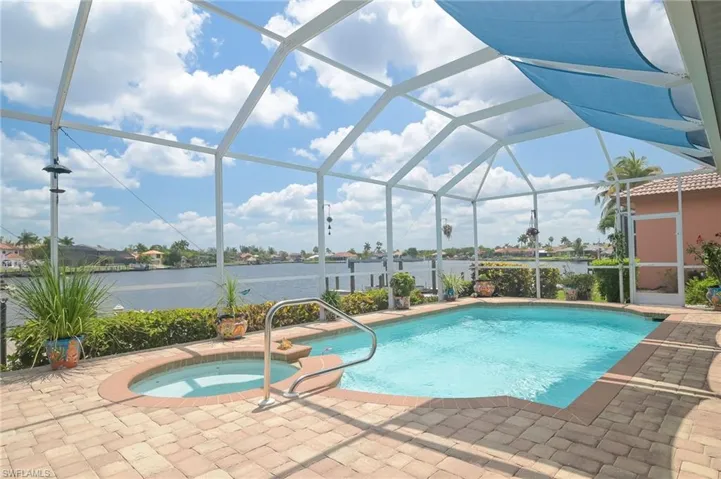 View of swimming pool featuring glass enclosure, an in ground hot tub, and a patio