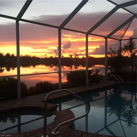 Pool at dusk featuring glass enclosure and a water view