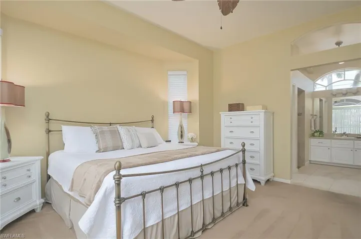 Bedroom with ceiling fan, ensuite bathroom, light carpet, and sink