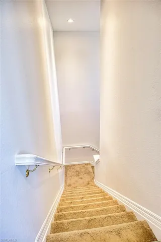 Stairs with a textured wall and baseboards