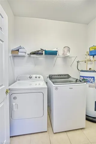 Washroom with light tile patterned floors, water heater, and independent washer and dryer