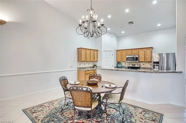 Dining space with light tile patterned floors, a towering ceiling, recessed lighting, and a chandelier