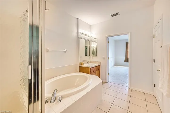 Full bath with a bath, vanity, and light tile patterned flooring