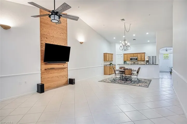 Living area featuring light tile patterned floors, a chandelier, a ceiling fan, high vaulted ceiling, and recessed lighting