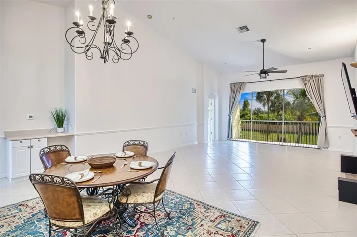 Dining room featuring light tile patterned floors, ceiling fan, arched walkways, and high vaulted ceiling