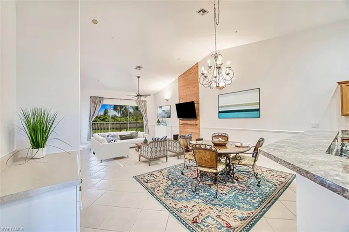 Dining room featuring a ceiling fan, light tile patterned floors, a chandelier, and high vaulted ceiling