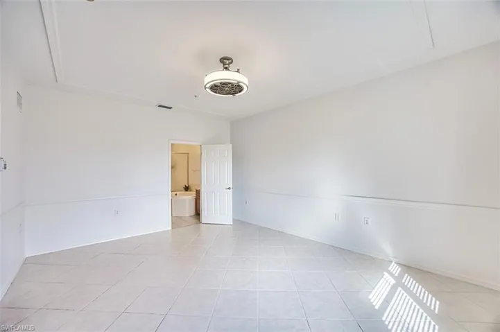 Empty room featuring light tile patterned floors and baseboards