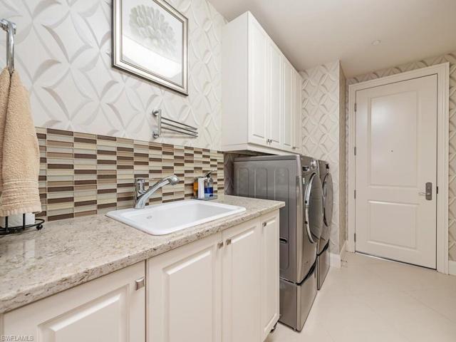 Large laundry with sink and customized for front loading washer/dryer on pedestals.  Storage closet.