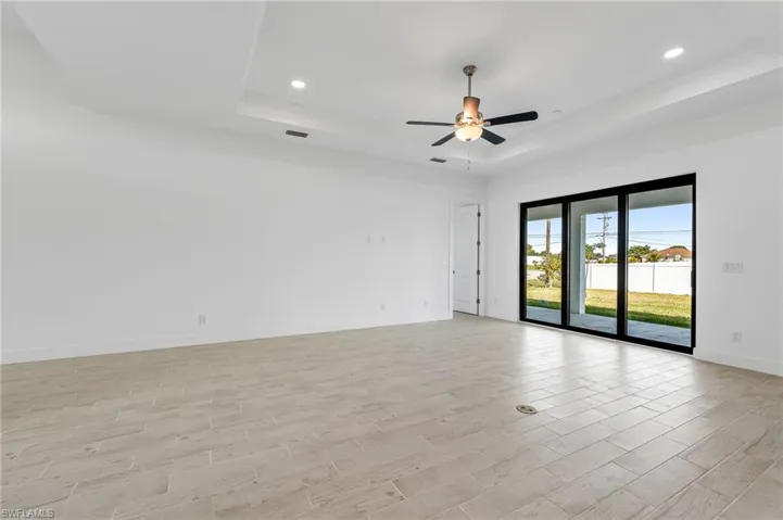 Unfurnished room featuring light wood-type flooring, a tray ceiling, and ceiling fan