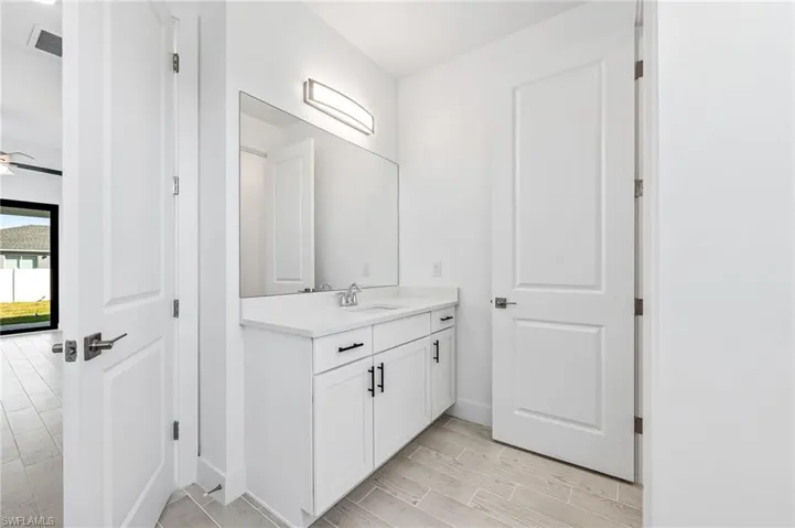 Bathroom with vanity with extensive cabinet space and ceiling fan