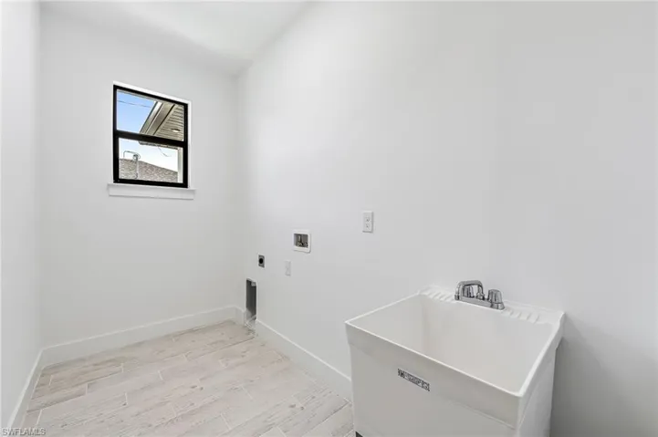 Clothes washing area featuring sink, hookup for a washing machine, light wood-type flooring, and electric dryer hookup