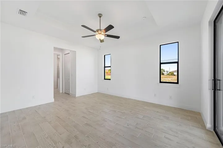 Spare room with ceiling fan, a raised ceiling, and light hardwood / wood-style floors