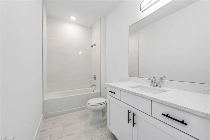 Full bathroom featuring tile floors, tiled shower / bath combo, vanity, and toilet