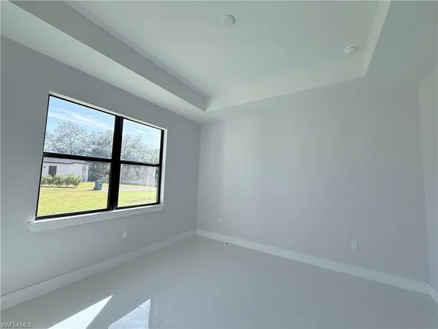 Tiled spare room with baseboards and a raised ceiling