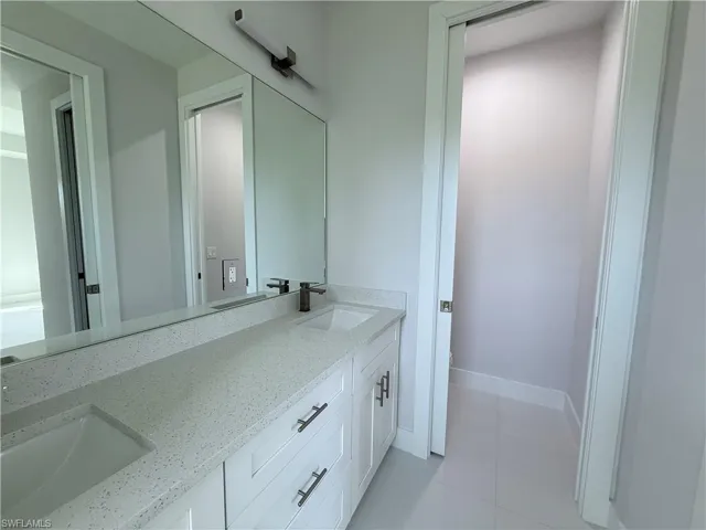 Bathroom with double vanity and light tile patterned floors