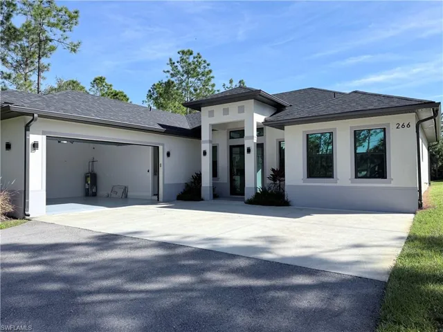 Prairie-style house with stucco siding, roof with shingles, and driveway