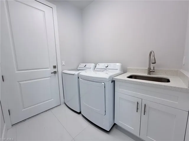 Laundry room with tile patterned flooring, washing machine and dryer, and cabinet space