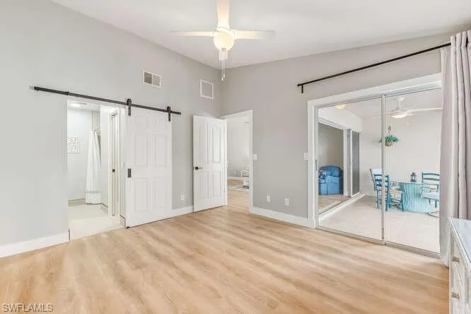 Master bedroom featuring new LVT flooring , a barn style door, a ceiling fan, lofted ceiling, walk-in closet, and ensuite bathroom.