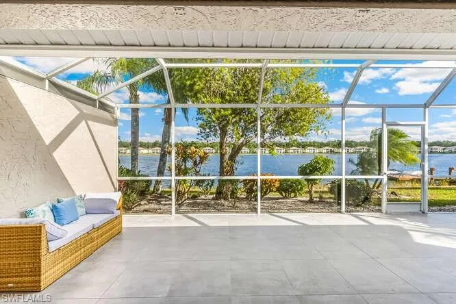 Screened lanai featuring new tile flooring, electric storm shutter, ceiling fan, and a water view.