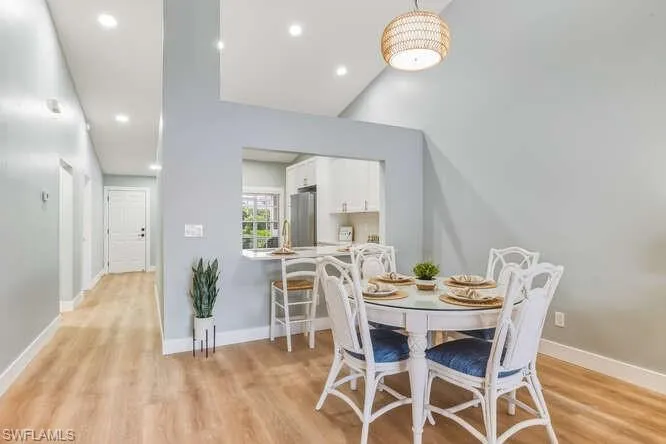 Dining area featuring LVT flooring, recessed lighting, and a vaulted ceiling.