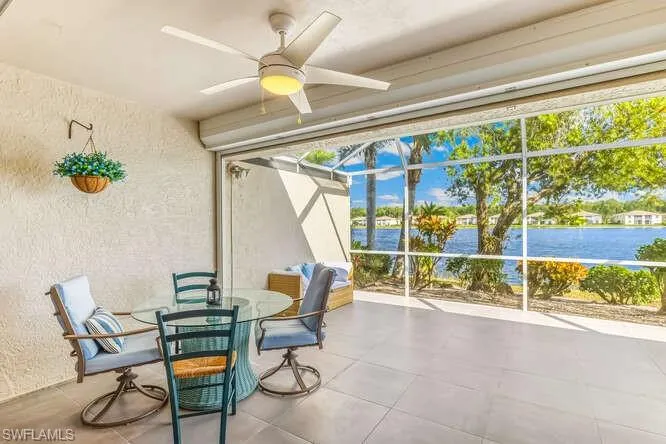Screened lanai featuring new tile flooring, electric storm shutter, ceiling fan. and a water view.