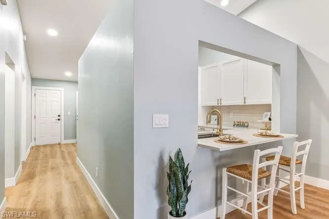 Hall featuring recessed lighting and new LTV flooring. Also, a breakfast bar area and view into kitchen area.