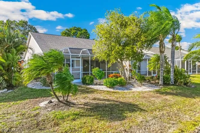 View of the back of property with a screened lanai, and landscaping.