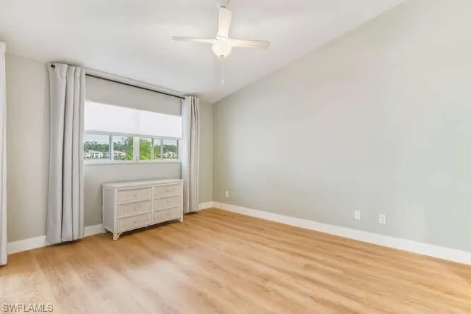 Master bedroom with new LVT flooring, ensuite bathroom, walk-in closet, ceiling fan, slider to lanai, and lofted ceiling.