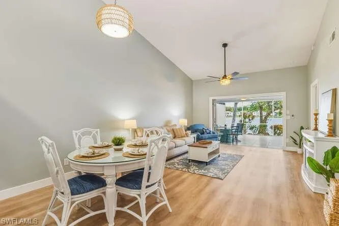 Dining space and living area with vaulted ceilings, new LVT flooring, recessed sliding door, and a ceiling fan.