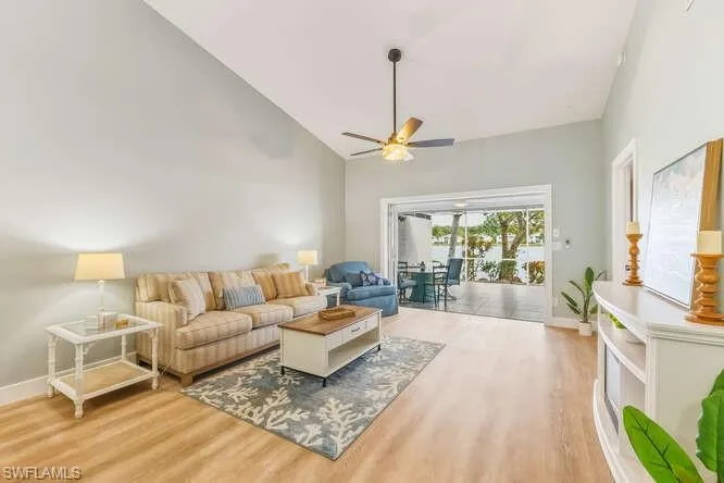 Living area featuring ceiling fan, high vaulted ceiling, and new LVT flooring, and sliding door out to the screened lanai.