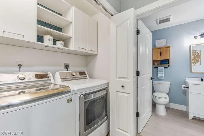 Laundry room with washer and dryer, new LVT flooring, and cabinet/storage space.