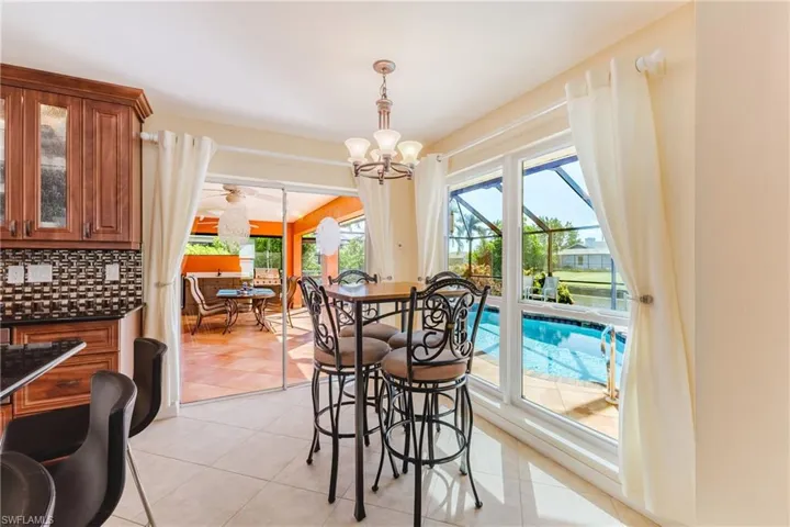 Dining space with light tile patterned floors, a chandelier, a ceiling fan, and a sunroom