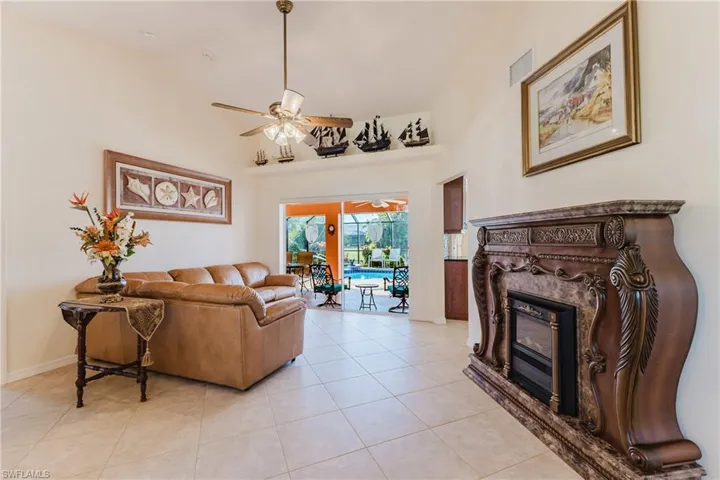 Living room featuring a ceiling fan, high vaulted ceiling, a fireplace, and light tile patterned flooring