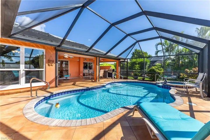 View of pool with a sunroom, a patio area, a lanai, a pool with connected hot tub, and a ceiling fan