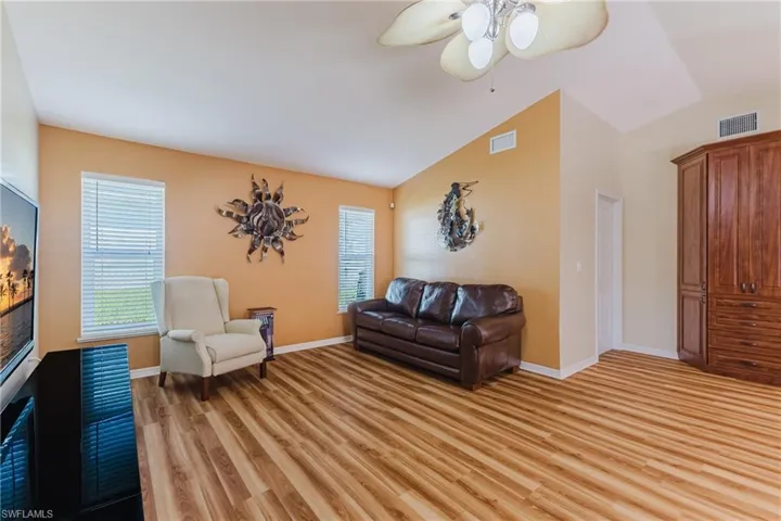 Living room with lofted ceiling, light wood-style flooring, and a ceiling fan