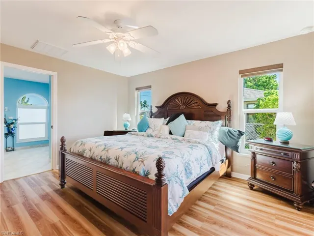 Mural Removed - Bedroom with multiple windows, light wood-style floors, and ceiling fan