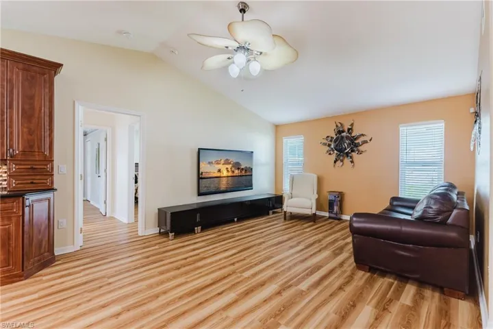 Living area featuring lofted ceiling, light wood-type flooring, and a ceiling fan