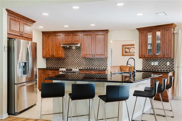 Kitchen featuring stainless steel appliances, backsplash, a kitchen bar, and recessed lighting