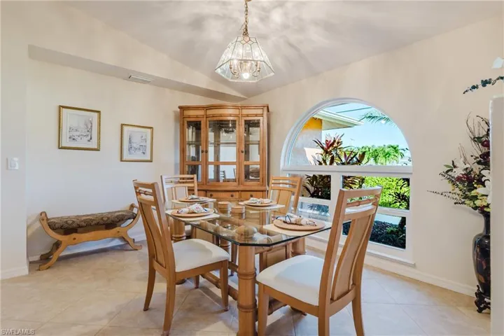 Dining room with light tile patterned flooring, a chandelier, and vaulted ceiling