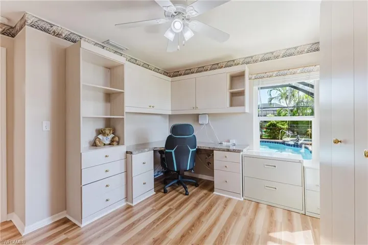 Office featuring light wood-style flooring, built in desk, and a ceiling fan