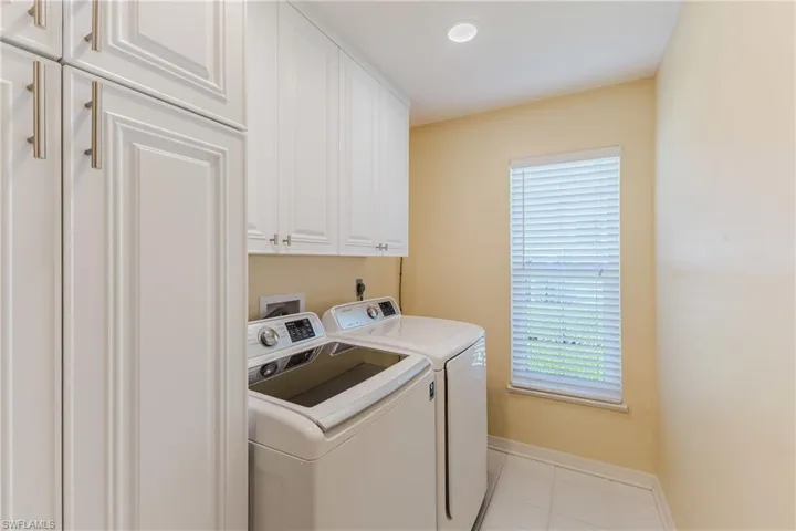 Washroom with light tile patterned floors, cabinet space, and washer and dryer