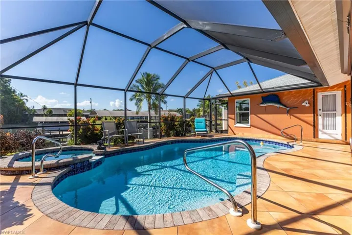 View of swimming pool with a sunroom, glass enclosure, a pool with connected hot tub, and a patio area