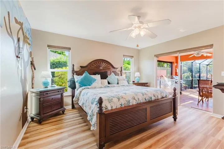 Bedroom with light wood finished floors, multiple windows, access to outside, and ceiling fan