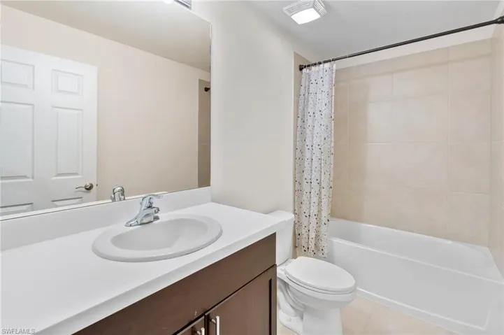 Bathroom with shower / tub combo, vanity, and light tile patterned flooring