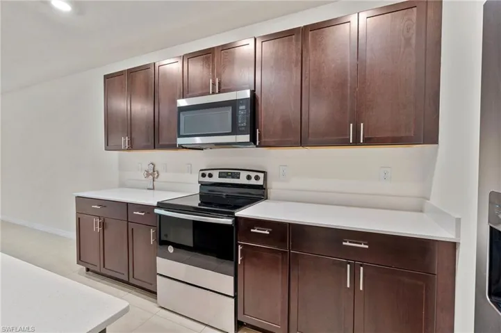 Kitchen featuring stainless steel appliances, dark brown cabinets, and light tile patterned floors