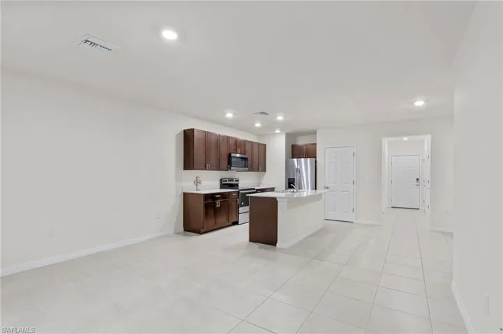 Kitchen with an island with sink, stainless steel appliances, dark brown cabinets, recessed lighting, and a kitchen breakfast bar