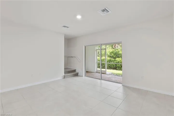 Empty room with light tile patterned floors and stairway