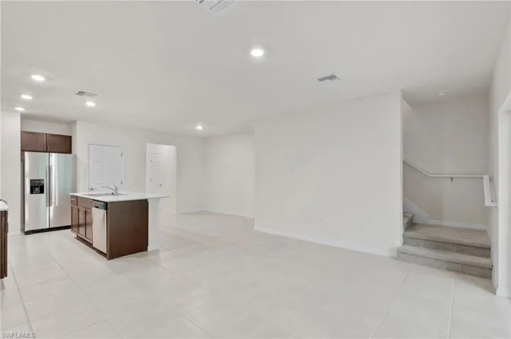 Kitchen featuring stainless steel appliances, an island with sink, dark brown cabinetry, recessed lighting, and light tile patterned flooring