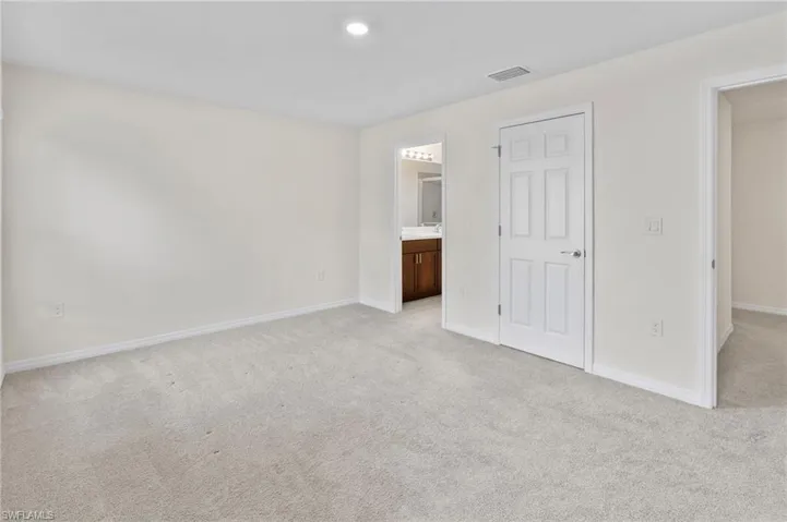 Unfurnished bedroom featuring light colored carpet and ensuite bath