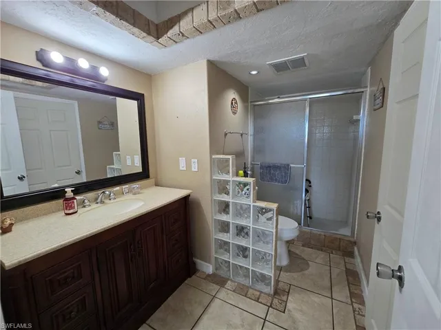 Vanity with ample storage, framed mirror, and a shower with sliding glass doors